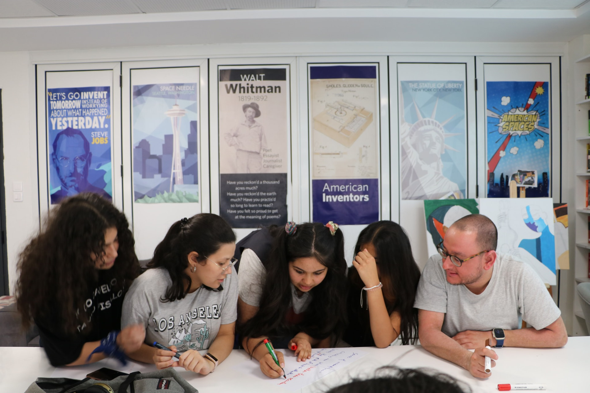 Young adults gathered around a table writing together on a large sheet of paper