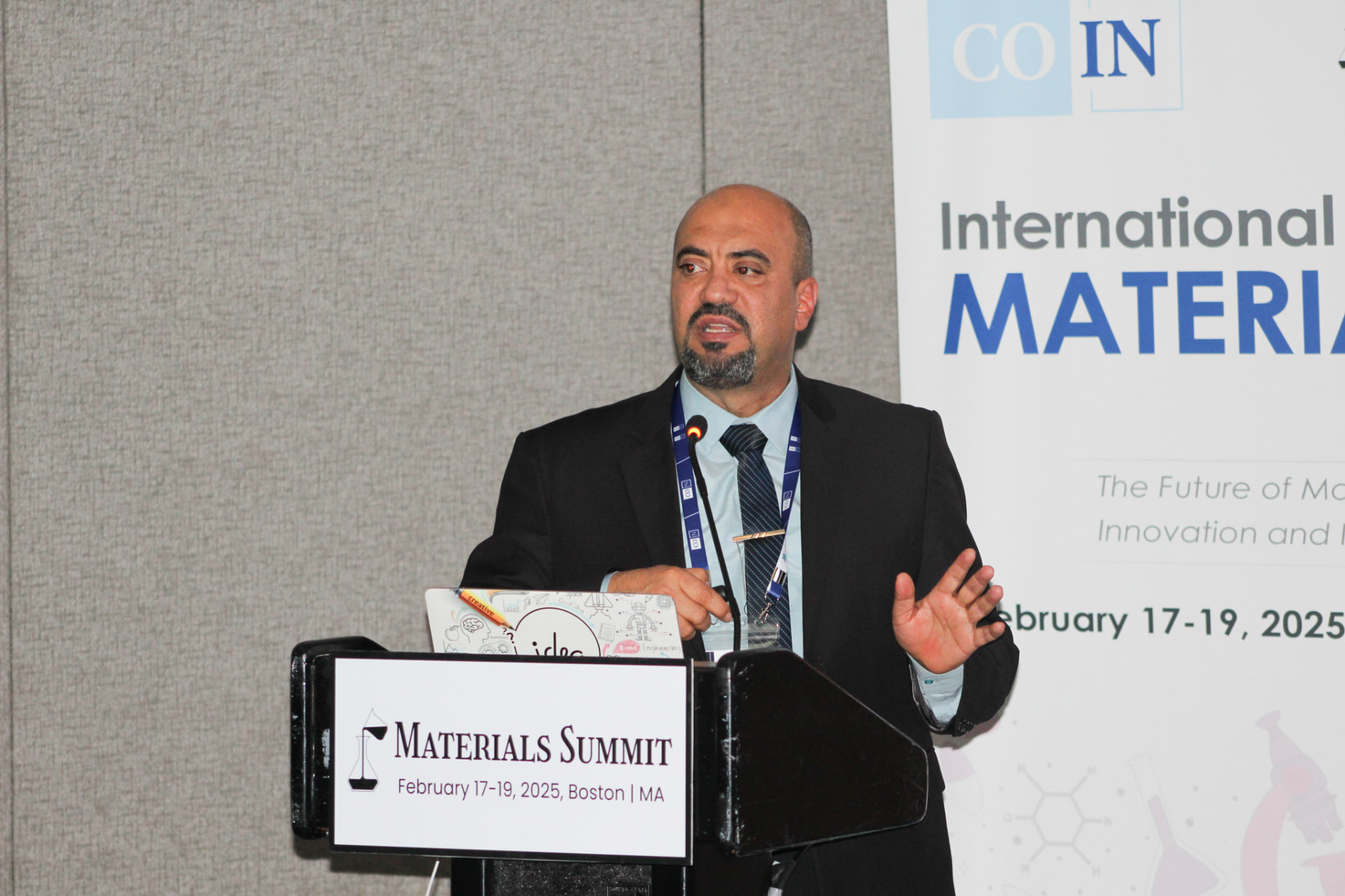 An alumnus presenting from a podium at the Materials Summit conference